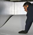 contractor installing TerraBlock™ floor insulation in a White City crawl space