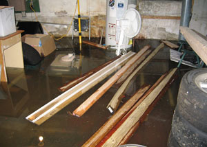 A severely flooding basement in White City, with lumber and personal items floating in a foot of water