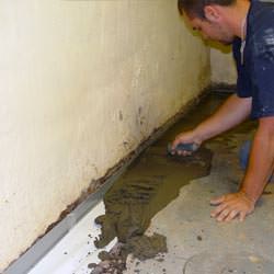 A basement waterproofer installing a perimeter drain system in Boissevain