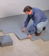 Contractors installing basement subfloor tiles and matting on a concrete basement floor in Dauphin, Saskatchewan and Manitoba