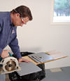 installing a waterproof vapor barrier on a basement floor to prepare for basement carpeting in a Estevan home