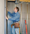 Insulated basement wall panels being placed against a concrete foundation wall in Virden